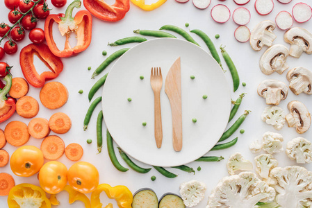 圆白板和新鲜有机蔬菜白色木制叉子和刀的顶部视图