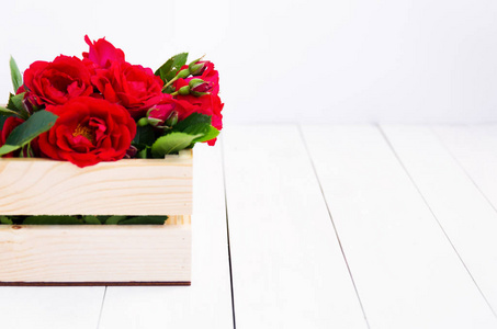 家里的玫瑰在一个木盒子上的白色木桌上。具有复制空间