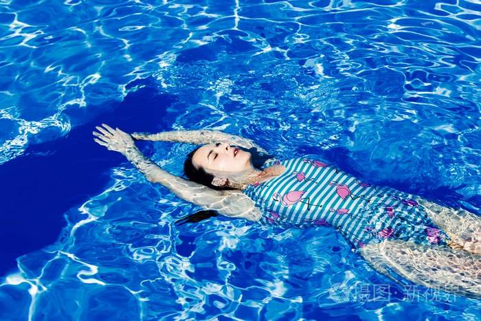 泳池透明水中有魅力的穿着泳装的年轻女子