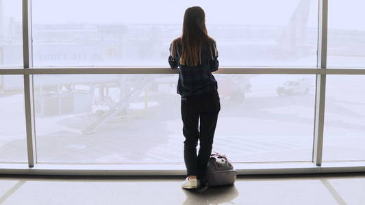 带背包的女人走到机场窗口。快乐成功的欧洲客运女孩与智能手机在终端。4k