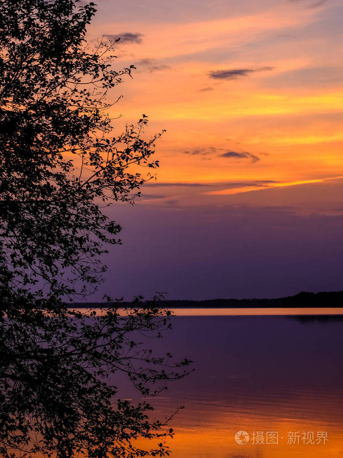 五颜六色的日落由湖与树剪影和红色天空在背景