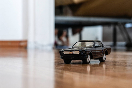 客厅里的地毯上留着儿童玩具。黑色汽车模型红外汽车坠毁在地板上