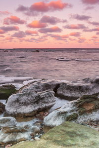 冰冷的石头在日落海海岸附近