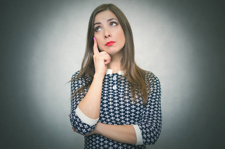 在寻找答案沉思的女人在灰色的背景下疑惑和思考.