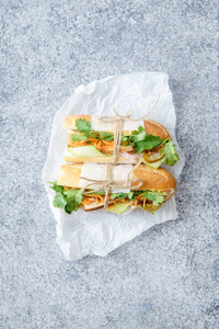 经典 banh 米三明治配以烤猪肉里脊和去皮黄瓜和香菜在白色厨房羊皮纸纸