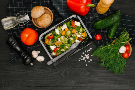 新鲜蔬菜沙拉在塑料容器在黑木桌