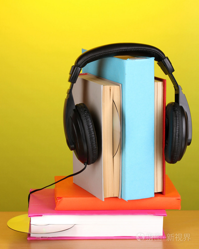 在绿色背景上的木桌子上的书上的耳机
