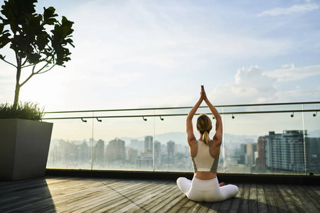 女性在活动磨损中的反观在冥想保持健康的生活方式中, 女孩在运动服有瑜伽训练早晨在摩天大楼屋顶感觉平静在都市