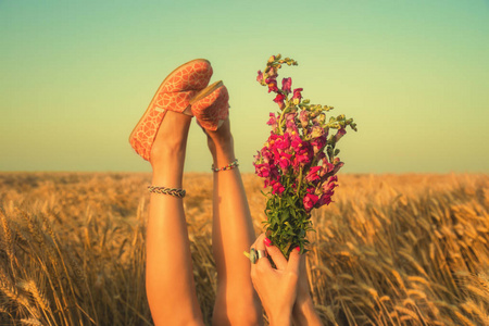 在麦田里躺着花花束的女人抬腿和手
