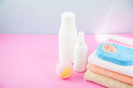 卫浴配件毛巾和洗发水, 沐浴泡沫, 奶油上的光, 明亮的蓝色和粉红色背景的概念, 照顾自己, 你的身体。复制空间
