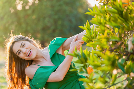 快乐的年轻女子, 在户外的夕阳下, 在一个橙色的果园, 微笑着。健康的生活方式概念, 皮肤和头发护理概念