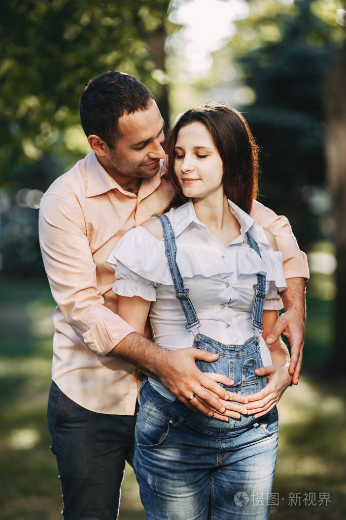 怀孕夫妇在公园散步, 拥抱
