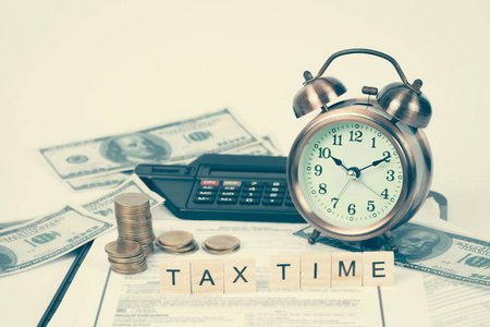 使用税务单据货币和闹钟在桌子上的措词税和计算器。税务概念