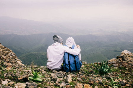 情侣相爱坐在山上的悬崖上