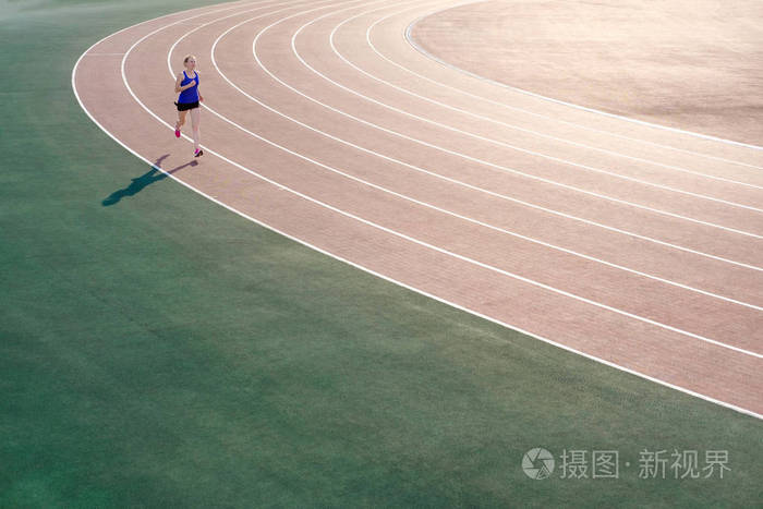 穿着粉红色运动鞋的运动年轻女子奔跑在跑道体育场上.概念运行