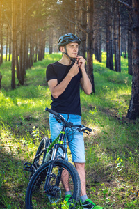 骑自行车的人在绿色自然的背景下戴着一顶运动的灰色头盔。自行车运动中的强制保护概念