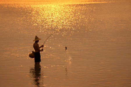 小男孩渔夫剪影日落钓鱼在湄公河在泰国老挝之间