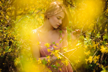 女孩站立在黄色开花树的分支之间