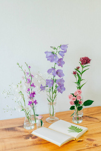 美丽的构图与香水样品和鲜花在桌子上。花在烧瓶里。野花。夏日花束。打开笔记本。植物