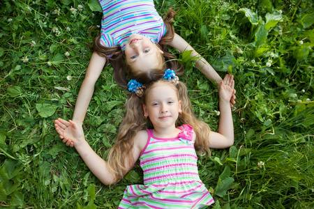 夏日公园里有两个美丽的小女孩躺在青草上