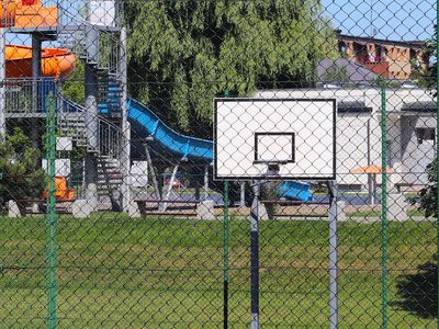 现代篮球场在小学的庭院.多功能儿童游乐场用人工表面围栏栅栏.