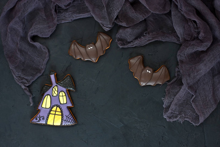自制的姜饼饼干万圣节的形式的房子和蝙蝠在黑暗的具体背景。顶部视图