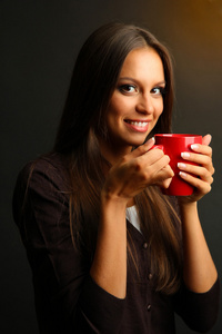 美丽的年轻女子，与杯咖啡，棕色背景上