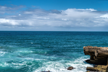 阳光明媚的夏日, 海浪拍打着大海的岩石海岸。