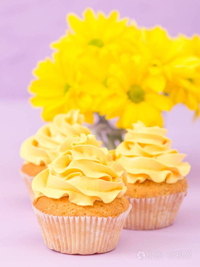 紫罗兰色背景的黄色奶油和菊花装饰的蛋糕