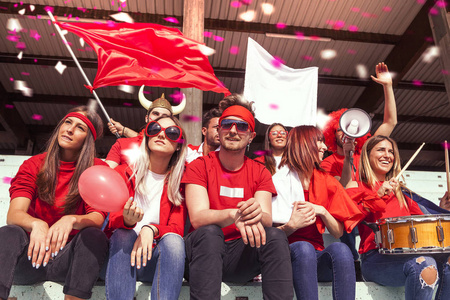 一群身着红颜色的粉丝观看体育场看台上的体育赛事