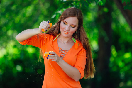 美丽的红色头发妇女的肖像按手两半的多汁美味的桔子在夏季绿色公园