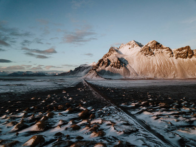 在冰岛 Stokksnes, 一条通向高山的道路, 覆盖着积雪。照片是用无人机拍摄的