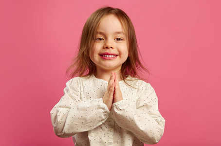 快乐的小女孩把手放在胸前的手掌上, 真诚地相信实现梦想, 许愿或祈祷