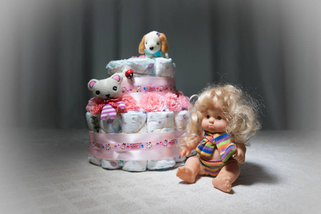 新生礼物概念。蛋糕的尿布。把尿布裹成蛋糕带花。蛋糕包装干净的尿布在桌子上, 婴儿娃娃装饰。选择性聚焦