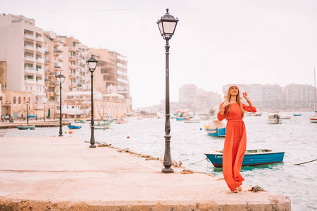马尔, 马耳他。2018年5月20日。美丽的女孩穿着红色的礼服走在船停靠在马耳他岛上