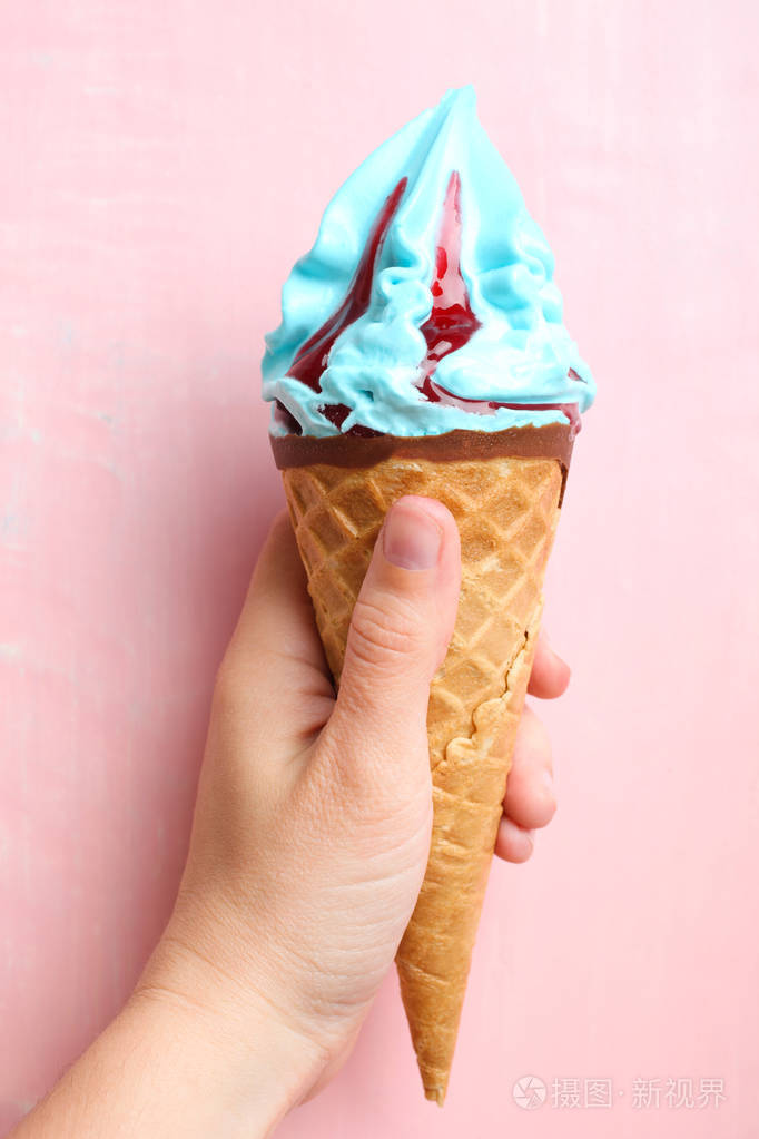 粉红色的背景下手上有果酱的蓝色冰淇淋