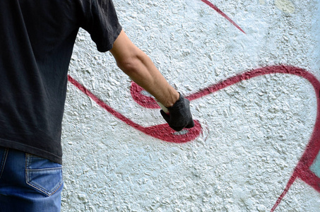 一个年轻的流氓在水泥墙上画涂鸦。非法破坏概念。街头艺术