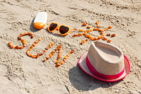 铭文和太阳的形状由琥珀石 太阳镜 太阳洗剂和稻草帽子在海滩 日光浴 夏天 度假的时间概念