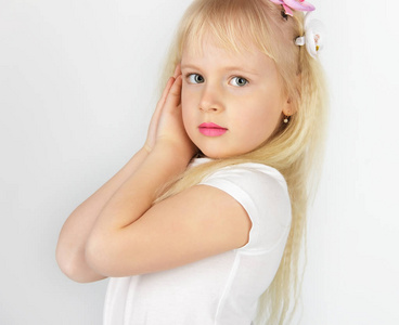 金发碧眼的小女孩双手合十祈祷上帝.一个小天使.侧面视图照片