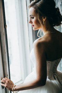 年轻美丽的新娘摆在窗口