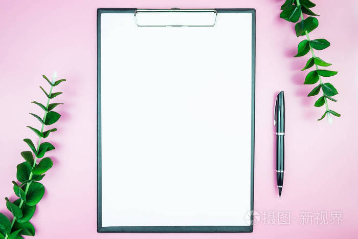 工作区与空白白纸免费空间和钢笔在办公桌上的粉红色粉彩背景的杂志