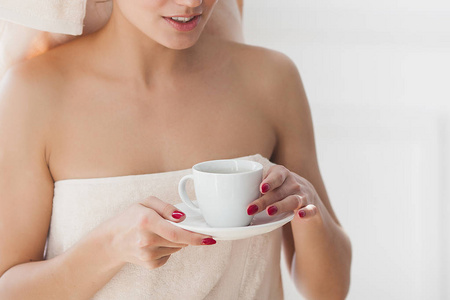 美丽的妇女在毛巾沐浴后喝了早晨的咖啡
