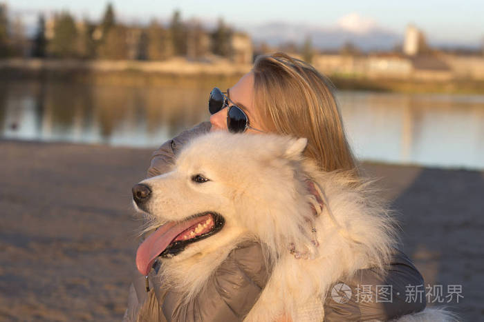 一个漂亮的女人搂着一只漂亮的萨摩耶狗