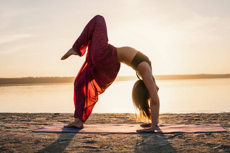 日落海滩上的剪影瑜伽女人
