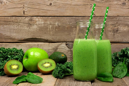 对菠菜的肉饼带甘蓝, 鳄梨, 菠菜, 苹果和猕猴桃的牛奶瓶中的绿色冰沙