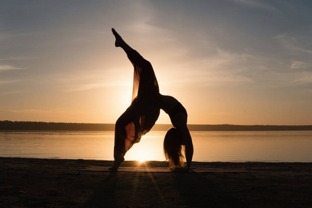 日落海滩上的剪影瑜伽女人
