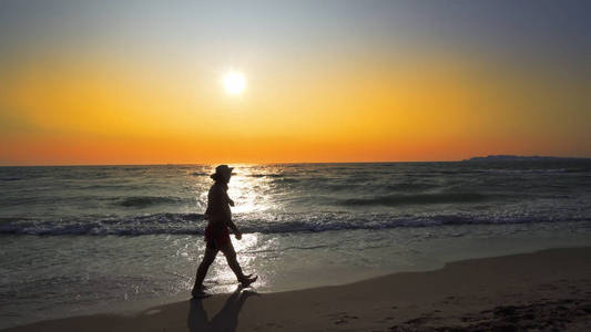 日落背景下沿夏日海滩漫步的情侣剪影