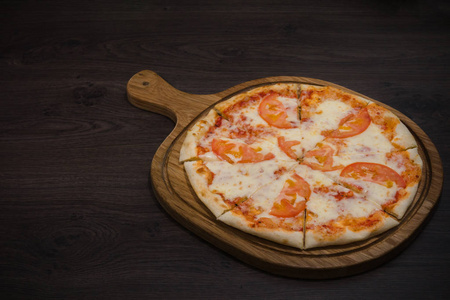 热的一块比萨与融化的奶酪在一个质朴的木桌上