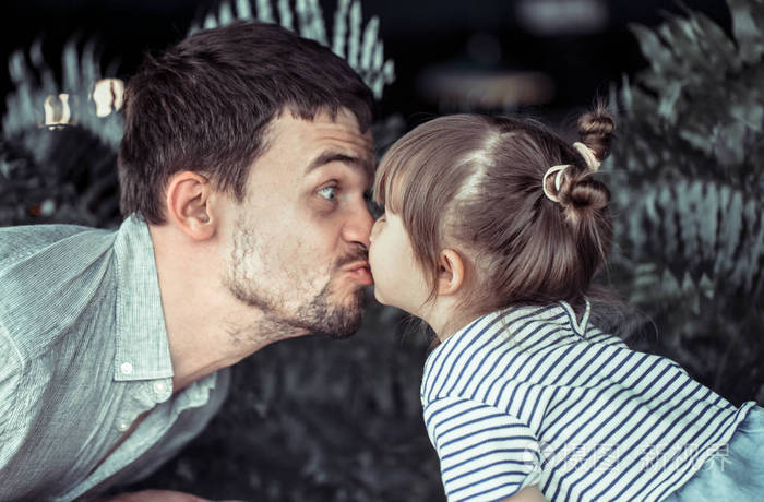 爸爸亲吻一个小女儿在咖啡馆的桌庆祝他的父亲天家庭价值