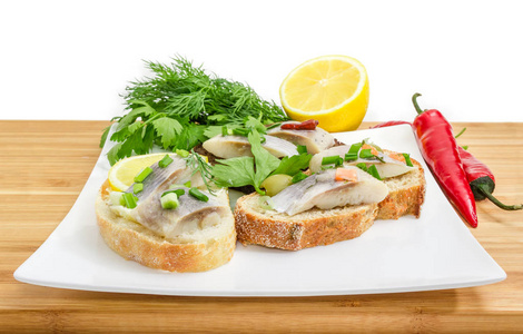 不同的开放式三明治与腌大西洋鲱鱼鱼片和各种面包的方形菜特写在木竹表面选择性聚焦